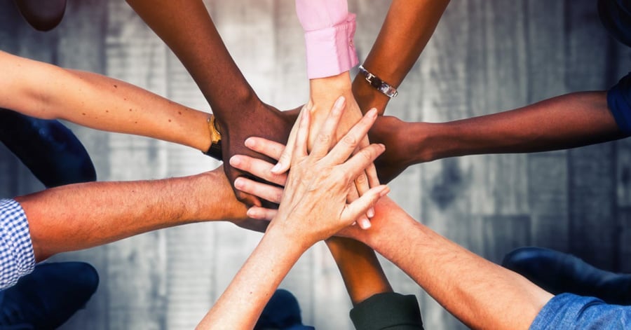 a-team-of-people-with-their-hands-in-the-middle