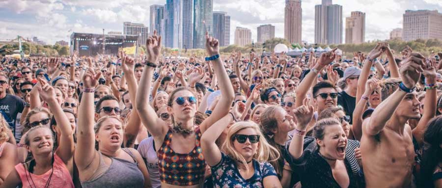 crowded people wearing wristbands raising hands
