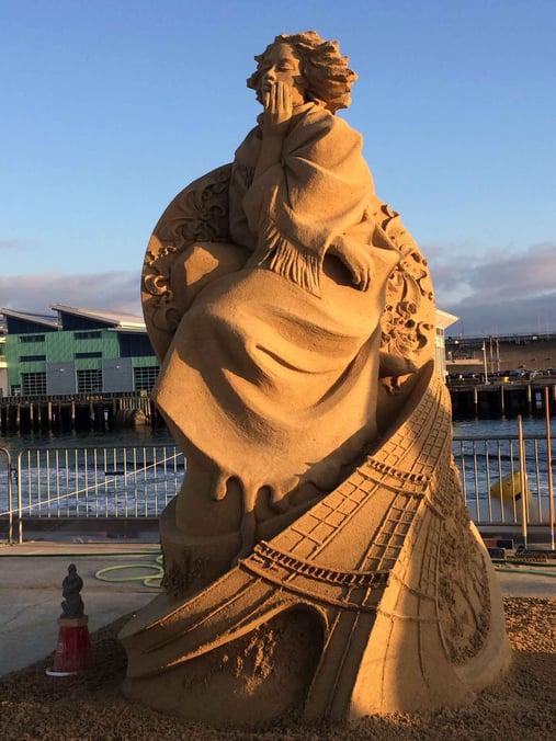 a woman sand sculpture illuminated at night